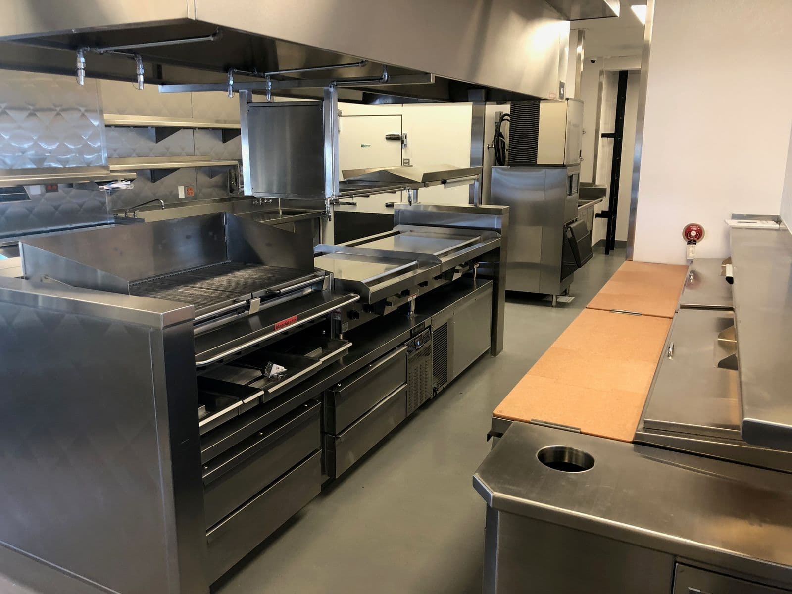 Commercial stainless kitchen with grills, griddles, and refrigerated prep stations